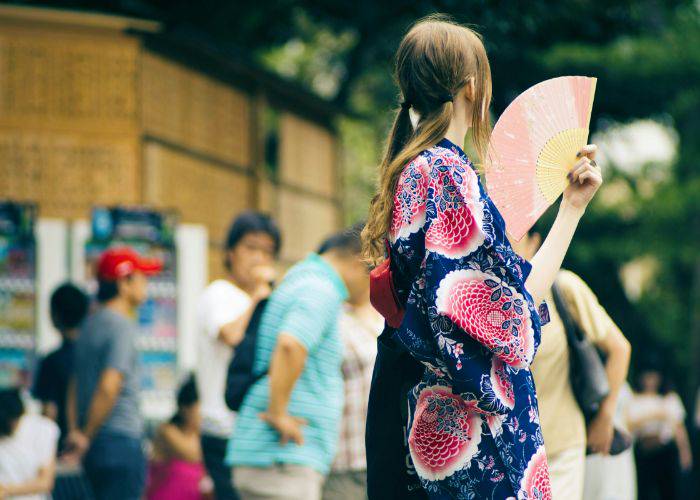 A woman fanning herself at a Japanese festival.